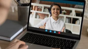 An employee having a video call facing a laptop with the video on