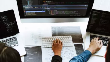 People working on laptops with coding software.