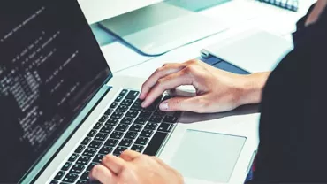 Person typing code on a laptop at a desk.