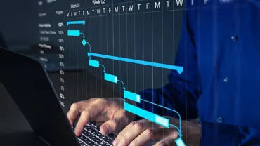 Person typing on a laptop with a Gantt chart displayed on screen.