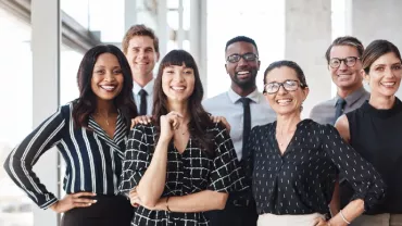 A group of smiling professionals in an office setting.