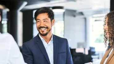 Smiling person in a business setting, shaking hands with a colleague.