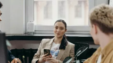 Three people having a discussion in an office setting.