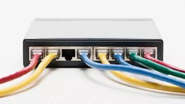 A network switch with five colorful Ethernet cables connected.