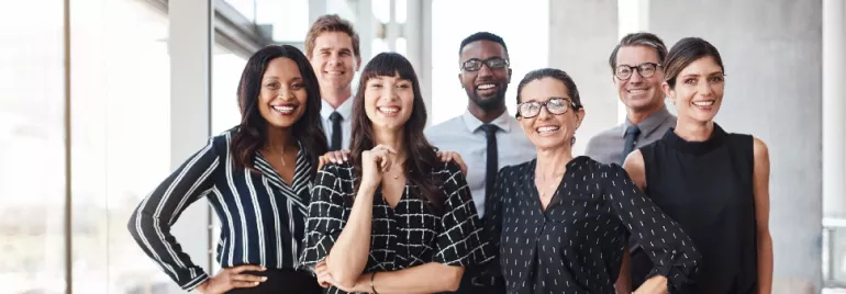 A group of smiling professionals in an office setting.