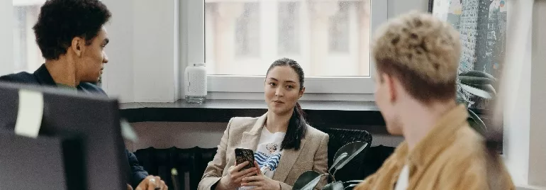 Three people having a discussion in an office setting.